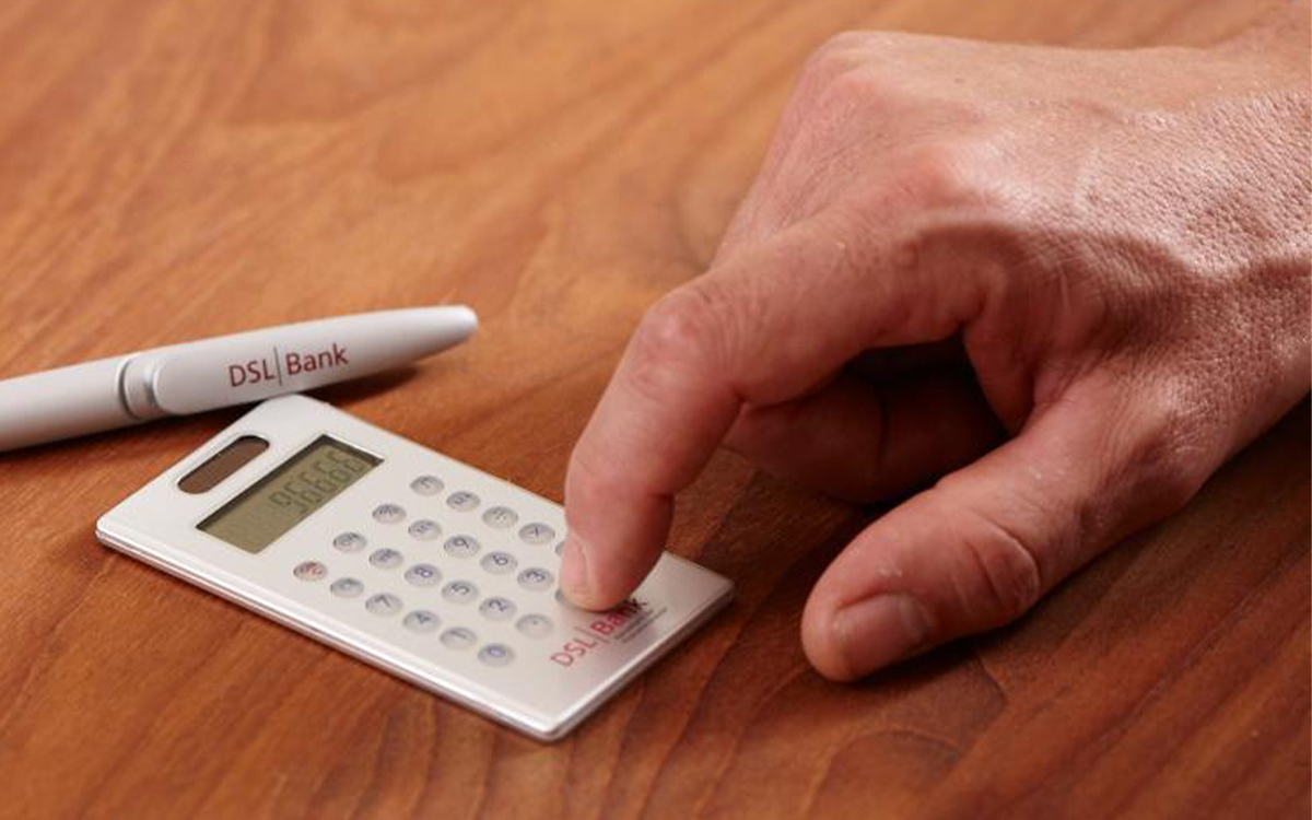 Finger tippt auf Taschenrechner, Kugelschreiber liegt daneben