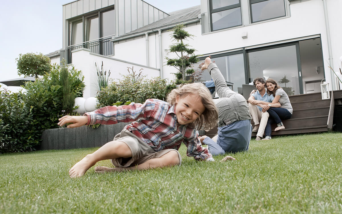 Junge spielt im Garten, Haus im Hintergrund